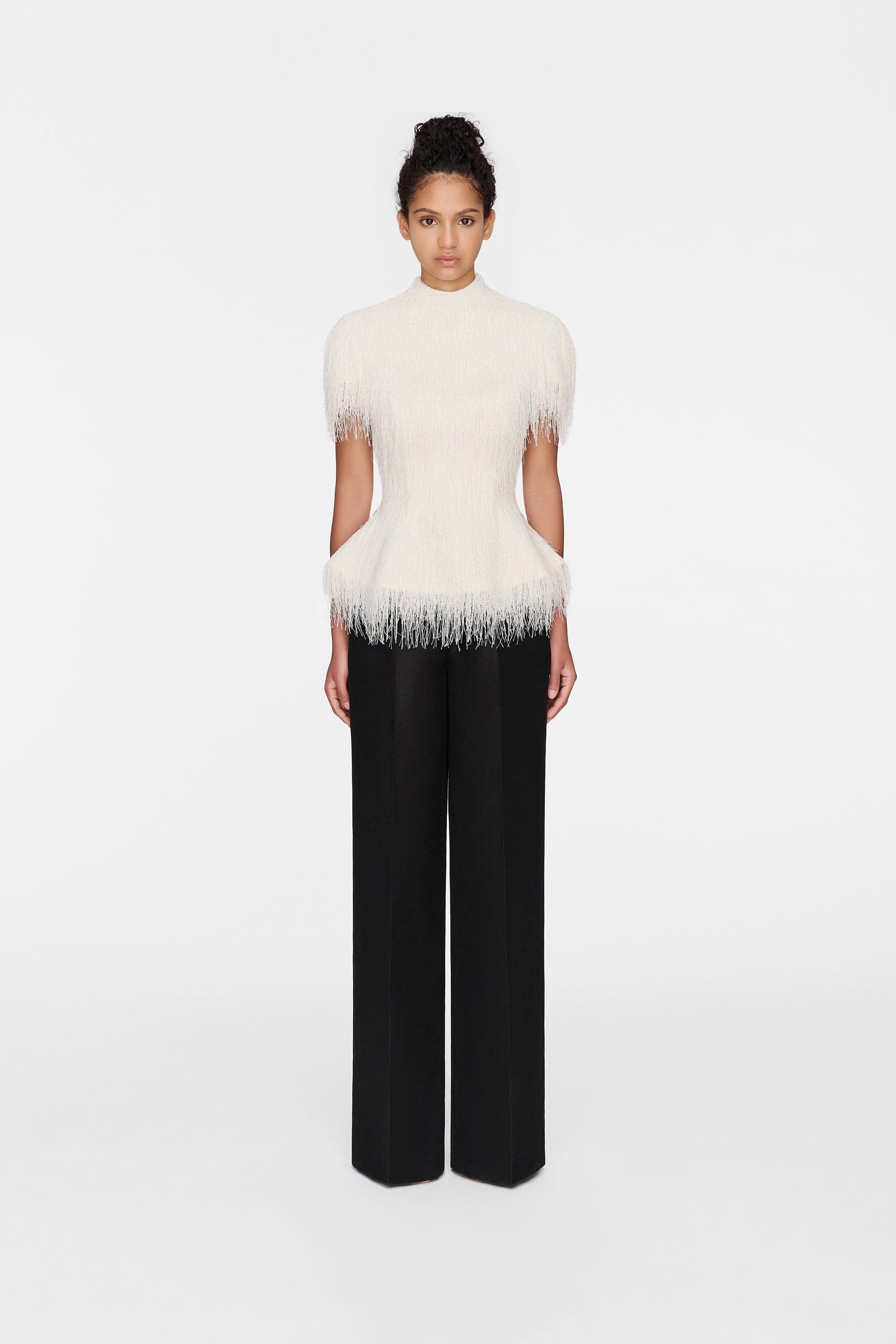 Woman in white feather top and black pants