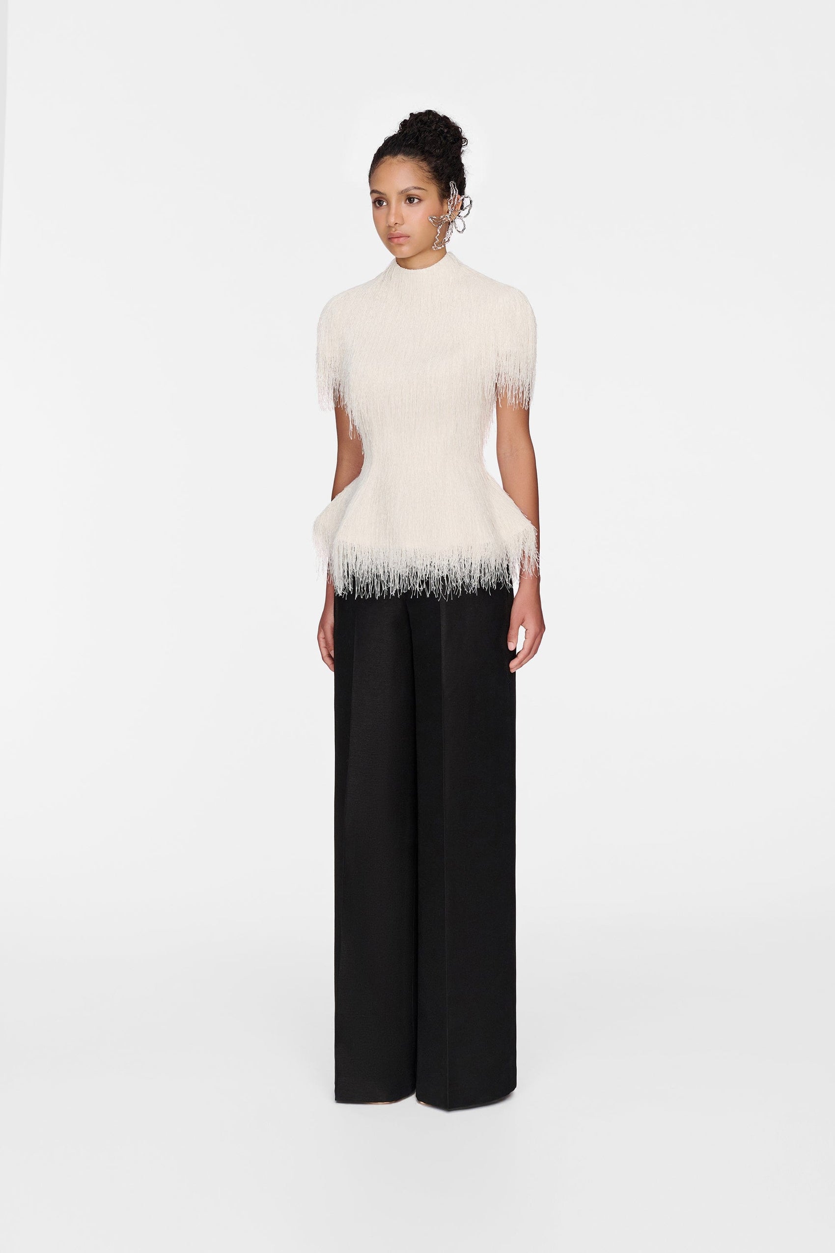Woman in white feathered top & black pants
