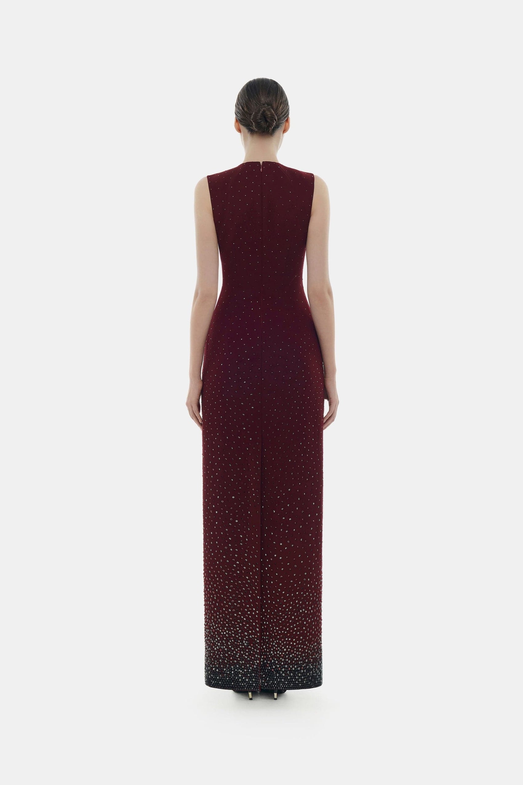 Woman in elegant burgundy gown, back view.