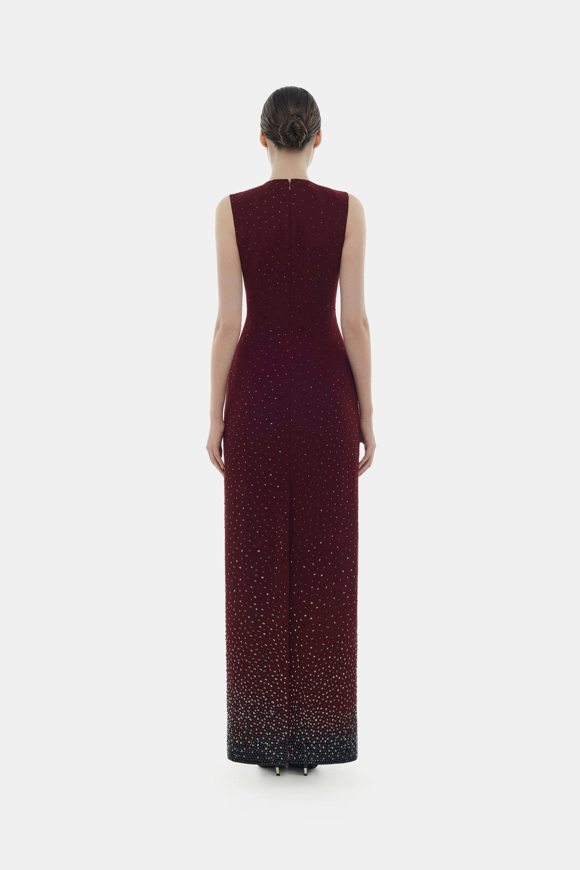 Woman in elegant burgundy gown, back view.